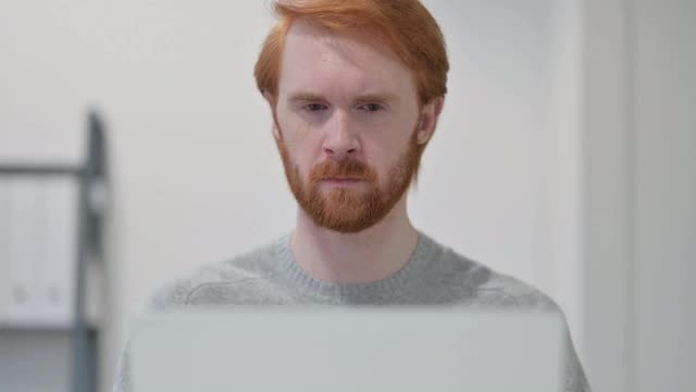 胡子红发男子使用笔记本电脑时头痛视频素材