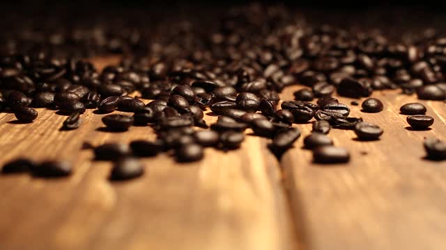 烤咖啡豆落在铺满咖啡豆的木桌上视频素材
