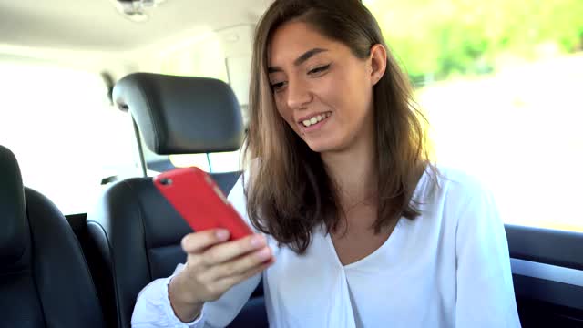 一个女人坐在汽车后座上用手机上网视频素材