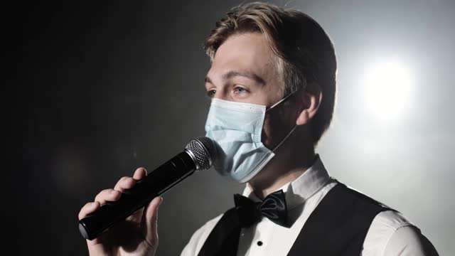 演出主持人带着医用口罩在舞台上对着麦克风讲话视频素材