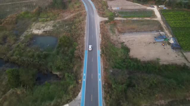 宽阔的无人机镜头跟踪一辆汽车在空旷的道路上被美丽的城外包围。视频素材