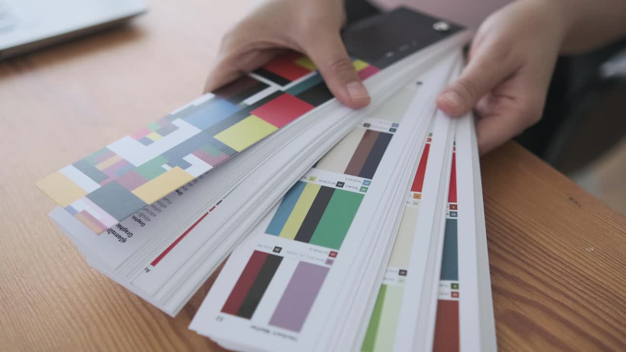 近女手的设计师选择颜色样本托盘创意装饰工作与色彩和谐，在办公室工作空间与电脑笔记本规划项目室内设计的成功。视频下载