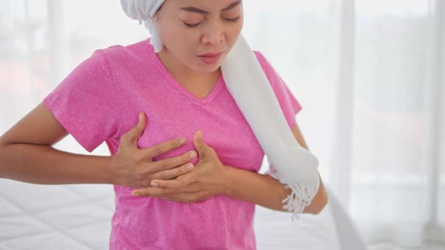 亚洲妇女乳房疼痛触摸胸部白色背景，不健康的女孩紧握胸部，感到急性疼痛，害怕心脏病发作，梗死或乳腺癌症状。视频下载