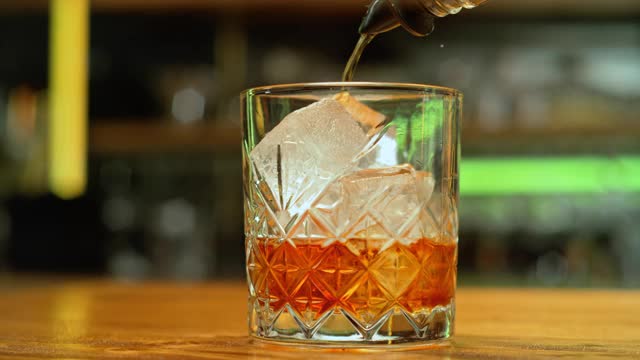 将威士忌倒入装有冰块的玻璃杯中视频素材