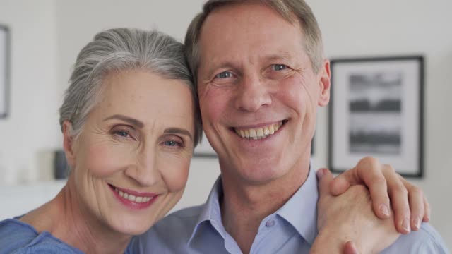 快乐老年成熟的60多岁家庭情侣拥抱，在家看着相机。视频下载