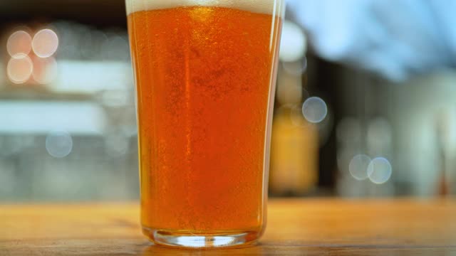 当啤酒被倒进玻璃杯时，气泡在流动视频素材