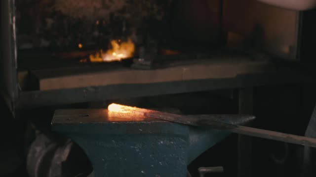 锻造车间。铁匠手工生产。铁匠用铁锤敲击灼热的金属，在铁砧上，进行锻造过程。视频素材