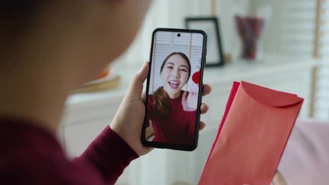 观点自拍视频通话的美丽迷人的年轻亚洲女士在红色春节庆祝服装快乐的微笑交谈和看相机手机祝农历节日。视频素材