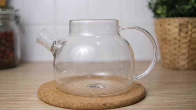 将茶倒入一个透明的玻璃茶壶中。准备啤酒。软木板。模糊厨房背景。视频素材