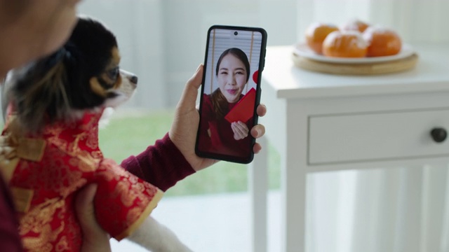 观点自拍视频通话的美丽迷人的年轻亚洲女士在红色春节庆祝服装快乐的微笑交谈和看相机手机祝农历节日。视频购买