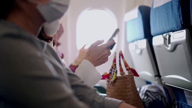 一名年轻女子戴着口罩坐在飞机座位上打电话视频下载