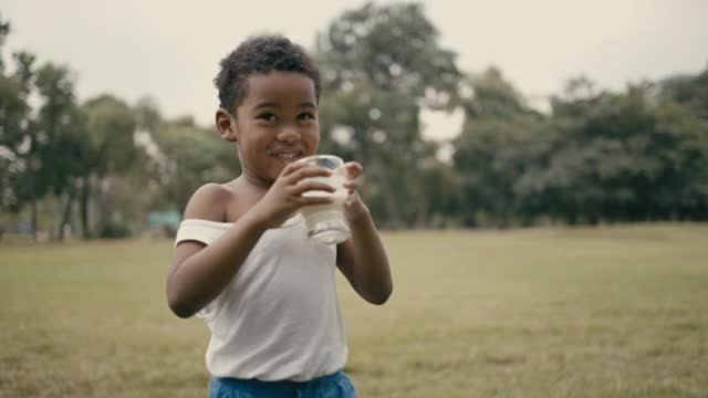 快乐的男孩在公园里喝牛奶视频下载