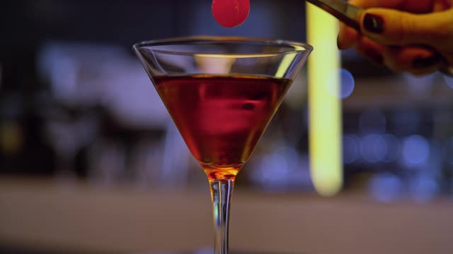 一个酒吧女侍将樱桃放入鸡尾酒的手视频素材