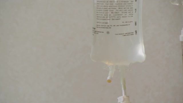 医院病人床边挂在杆子上的静脉输液袋;护士的手触摸并检查输液的各个方面。视频素材