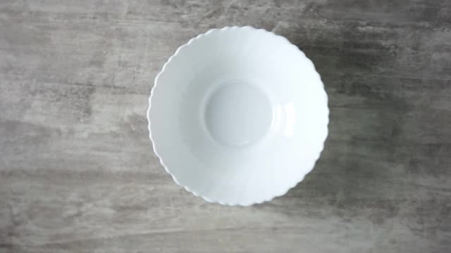 在上面拍摄的慢镜头中，玉米片落在木桌上的一个白色盘子里视频下载