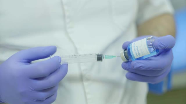 医生将新冠肺炎疫苗注射到注射器中视频素材