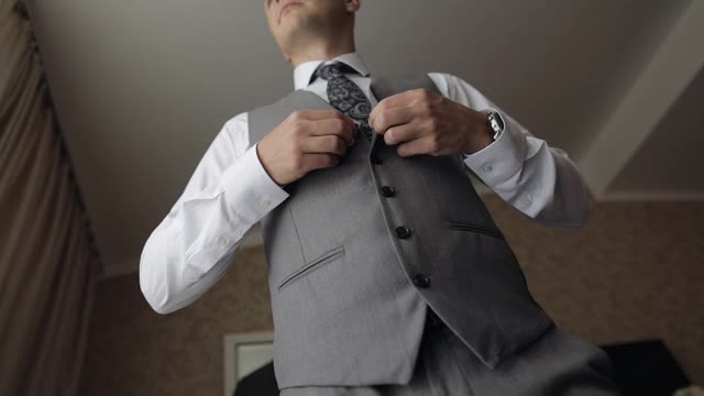 一名穿西装的男子双手合在胸前扣好上衣的扣子，准备出门视频素材
