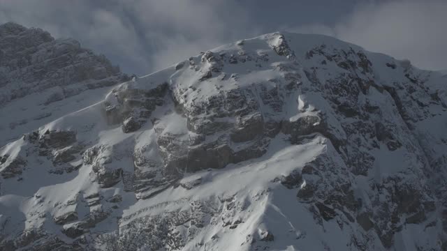 无人机飞行接近雪山和风山顶与落基山脉的背景视频素材
