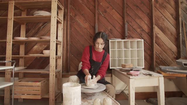 年轻女子在她的工作室里制作陶器轮视频素材