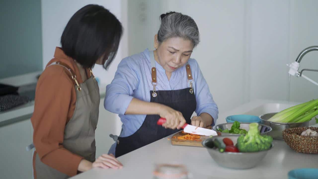 一位亚洲华人奶奶在厨房教孙女切菜视频下载