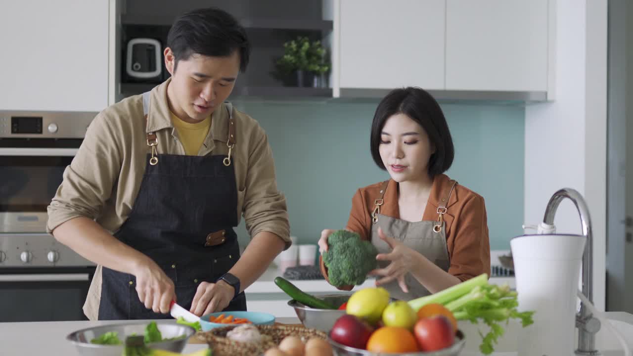 快乐的亚洲华人夫妇在厨房切菜视频下载