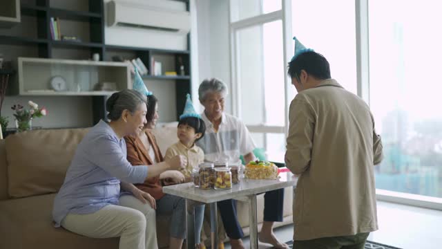 亚洲华人父亲在儿子的生日庆典上给他的父母送蛋糕视频素材