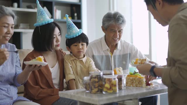 亚裔华人父亲在儿子的生日庆典上给儿子送蛋糕视频素材