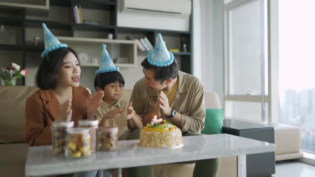 可爱的亚洲华人小孩和他的父母一起庆祝他的生日蛋糕视频素材