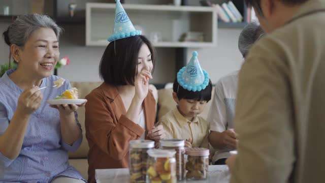 在儿子的生日庆典上，亚裔华人爸爸给他的妻子蛋糕视频素材