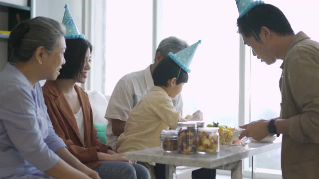 亚洲华人父亲在儿子的生日庆典上给他的父母送蛋糕视频素材