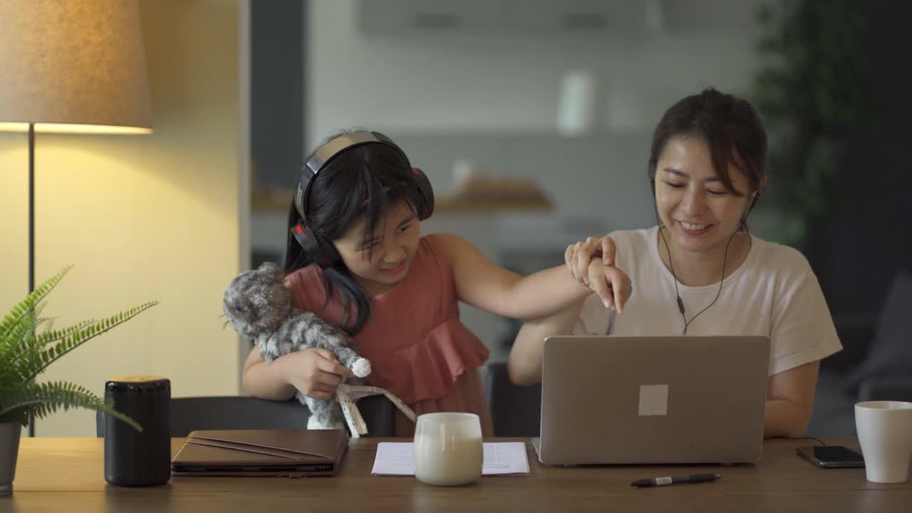亚洲华人女性在家工作，与可爱的女儿在客厅享受快乐时光视频下载