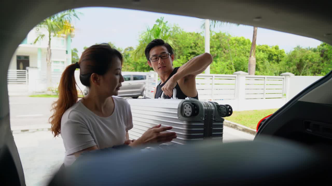一对亚洲中国夫妇带着他们的女儿从家里的车上卸下行李视频素材