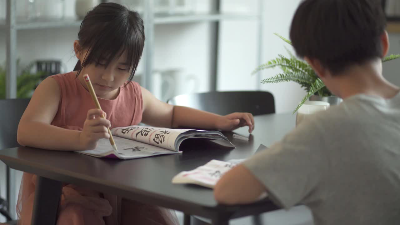 亚洲华人兄弟姐妹在家里练习书法视频素材