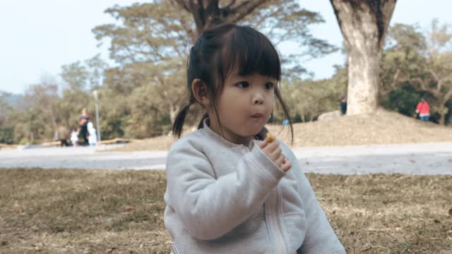 可爱的中国女孩在公园里吃早餐和野餐视频素材
