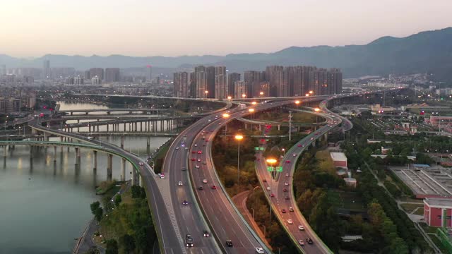 无人机视角观察黄昏时城市水边高架路的交通流视频下载