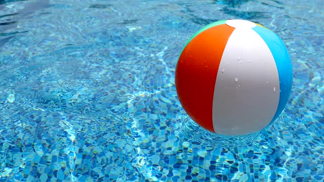 游泳池里的沙滩球。彩色充气球漂浮在游泳池。视频下载