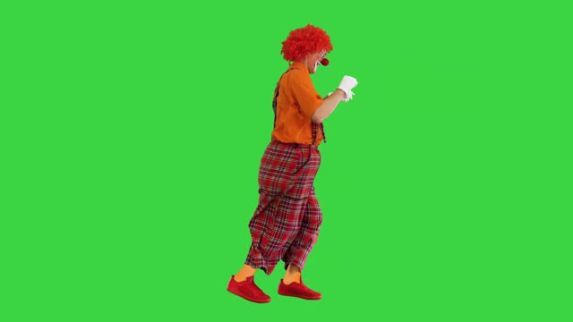 快乐的小丑在绿色屏幕上行走时竖起大拇指，颜色键视频素材