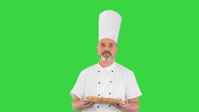 高级厨师手里拿着披萨走在绿屏上，色度钥匙视频下载
