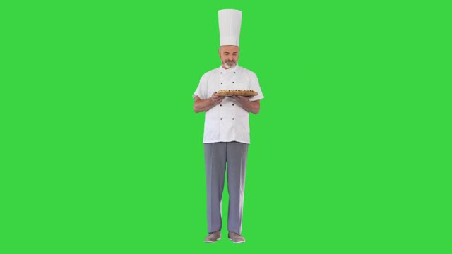 快乐的厨师闻着披萨，在绿屏上给你，色度钥匙视频素材