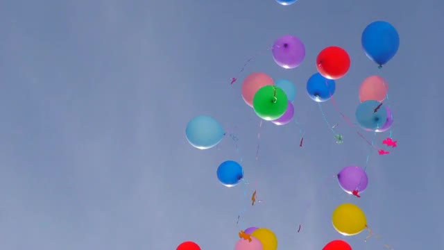 五颜六色的气球在蓝色的天空中飞翔。视频素材