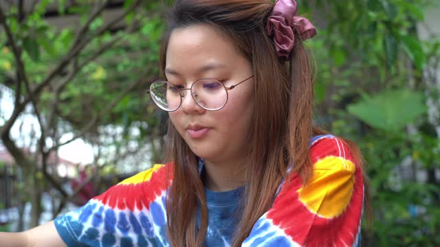 年轻的亚洲妇女练习在白色t恤上处理扎染织物在家里，家庭教育的概念视频下载