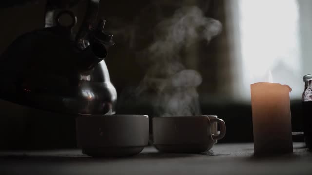 女人把热茶从茶壶倒进杯子里。在家的温馨心情。冬天的假期。关闭了。热水中的蒸汽。视频素材