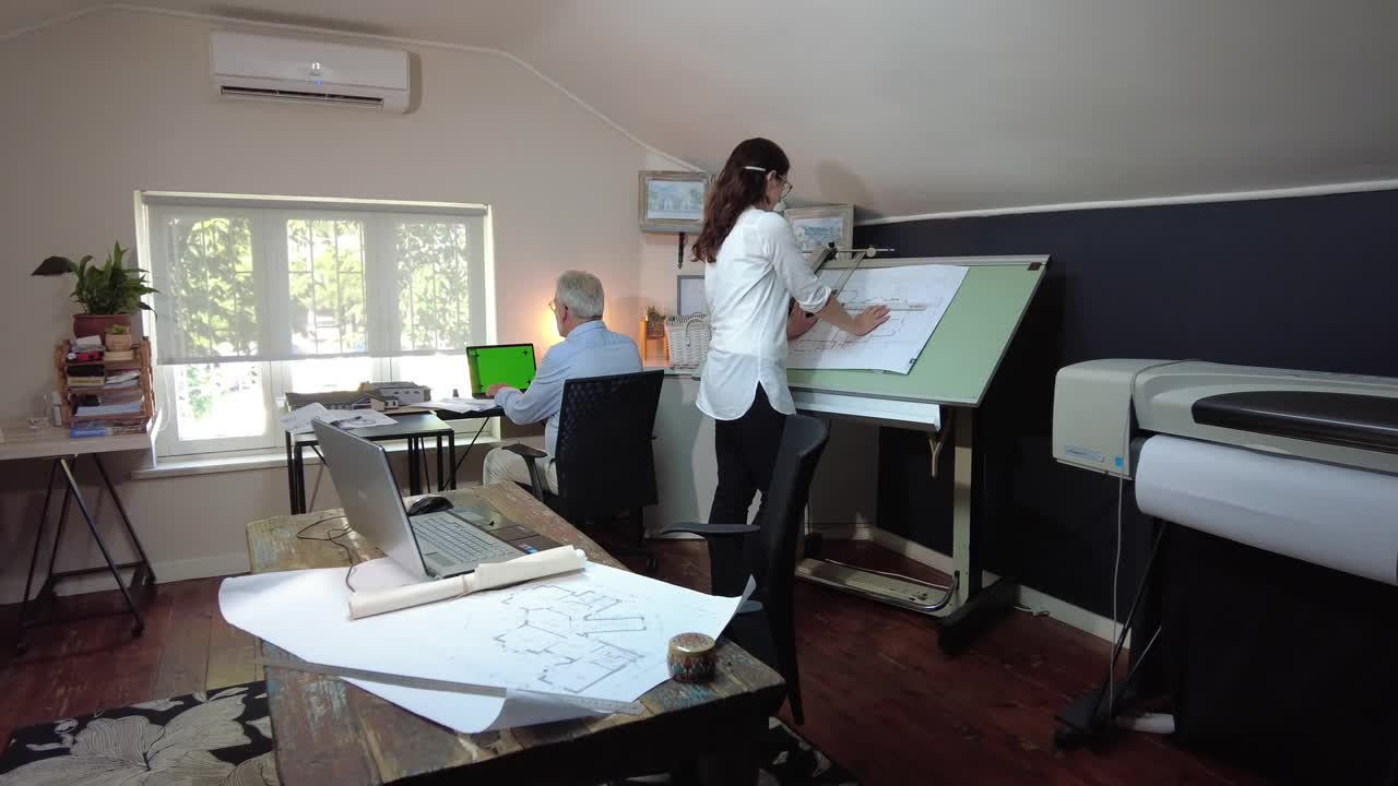 多莉在拍摄的年轻女建筑师工作的笔记本电脑在办公室与建筑计划开放视频下载