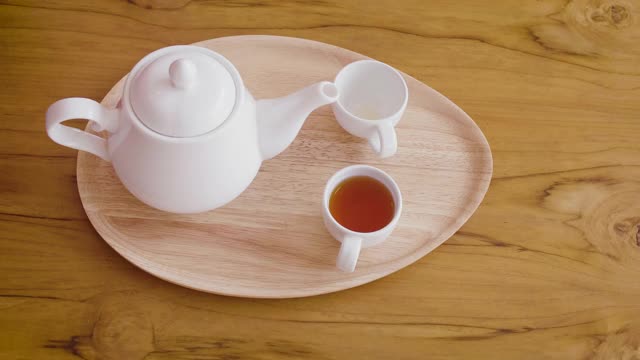 女子从茶壶倒进木桌上的茶杯中，茶道概念视频素材