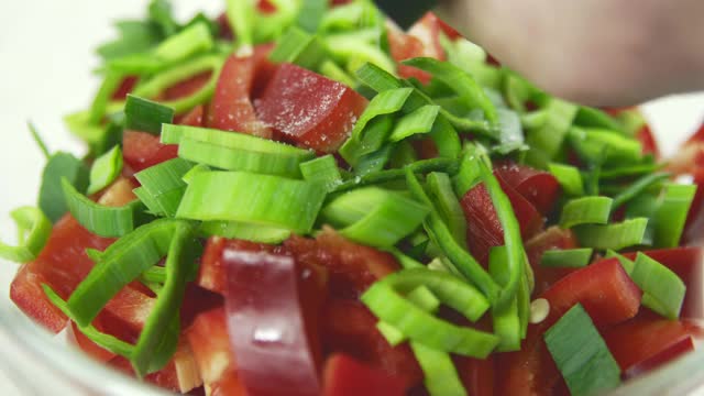 厨师用胡椒、洋葱和西红柿腌制新鲜沙拉的特写镜头。视频素材