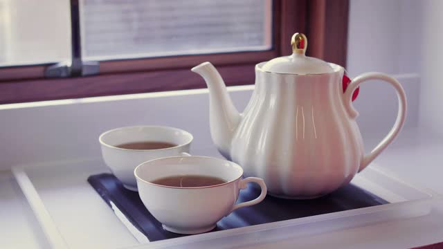 一个茶壶和茶杯放在木桌上，茶道概念视频素材