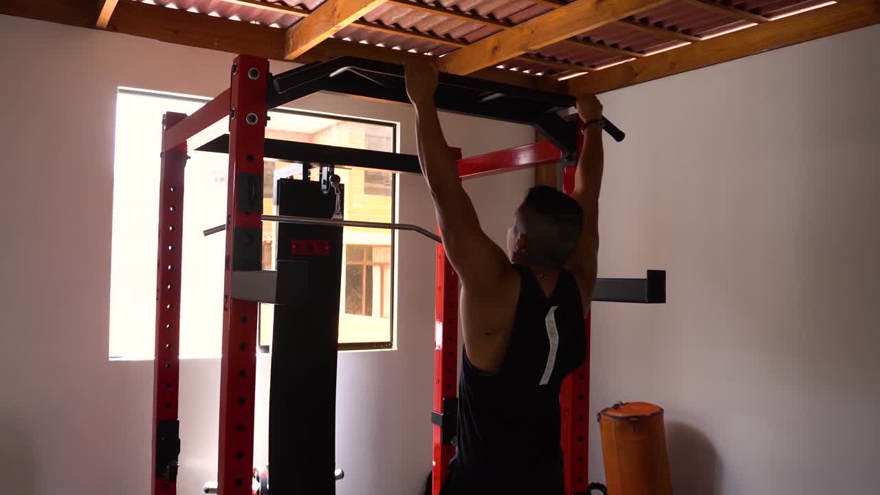 一个肌肉男做引体向上练习的特写从后面看到视频素材