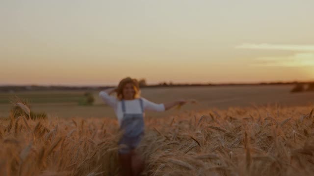 无忧无虑的妇女拿着麦子和草帽跑过麦田视频下载
