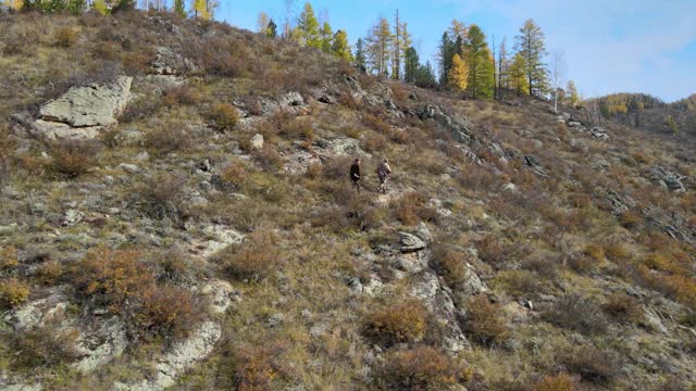 猎人手持武器沿着山腰行走，这是秋天的季节视频下载