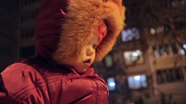 一个小女孩在一个冬天的晚上散步。视频下载